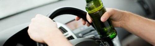 man driving while drinking alcohol
